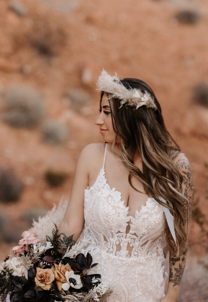 Bride looking off into the distance. Holding a bouquet to her side and a head piece. 