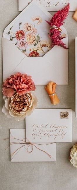 Close up of invitations with pink flowers and calligraphy written address. 