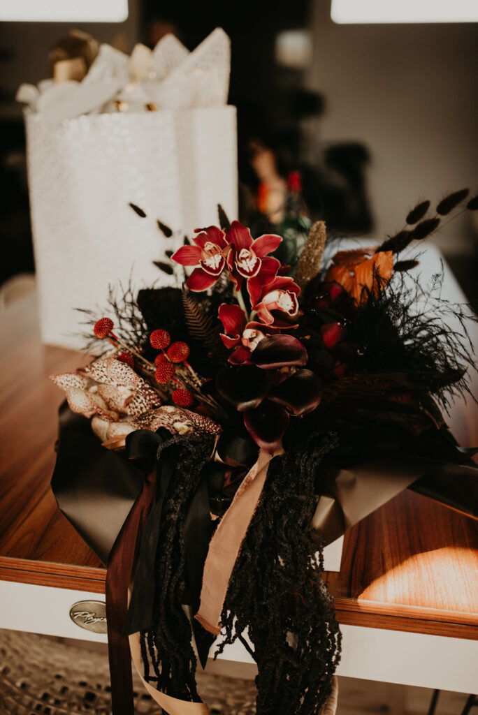 Dark and moody wedding bouquet. With bright reds, tan, and black flowers. 