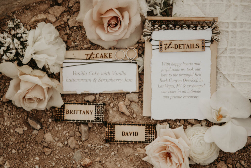Different Parts of an Invitation Suite close up of the details section. Laid out with creamy, blush roses on the desert floor. 