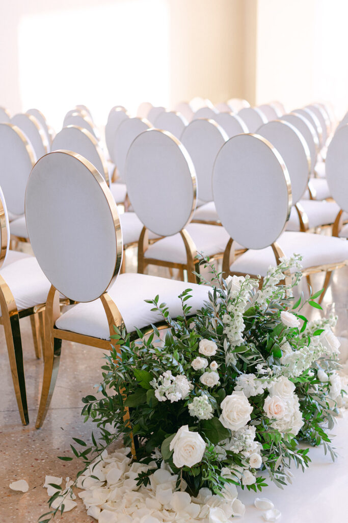 Aisle: Circle Or Runway? White rose and green floral ground display with perfectly lined white and gold chairs. 
