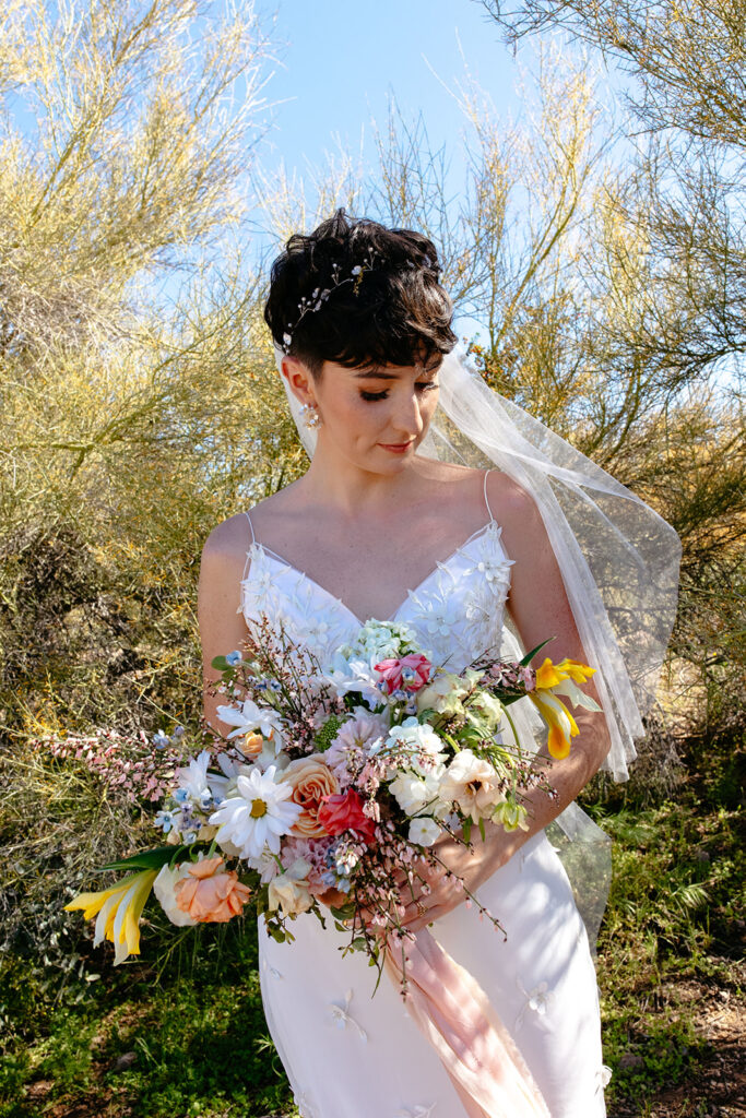 Short haired bride with a headband and simple veil accessory. Gorgeous wild flower bouquet with fitted wedding dress