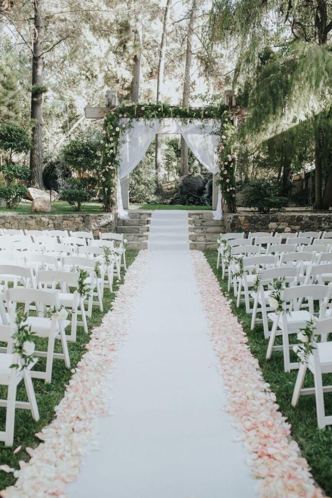 Traditional runway aisle with silk white runner and petals lining the sides. 