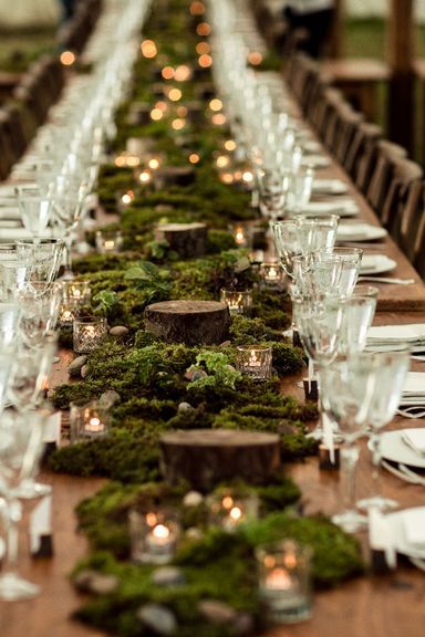 Green mossy, forest themed reception tables with tee lights and small round tiny logs. 