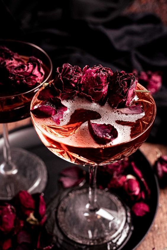 Unveiling the Magic: The Art of Styling a Themed Wedding close up of a maroon cocktail with sparkling rose wine, black cassis, and a little rose syrup