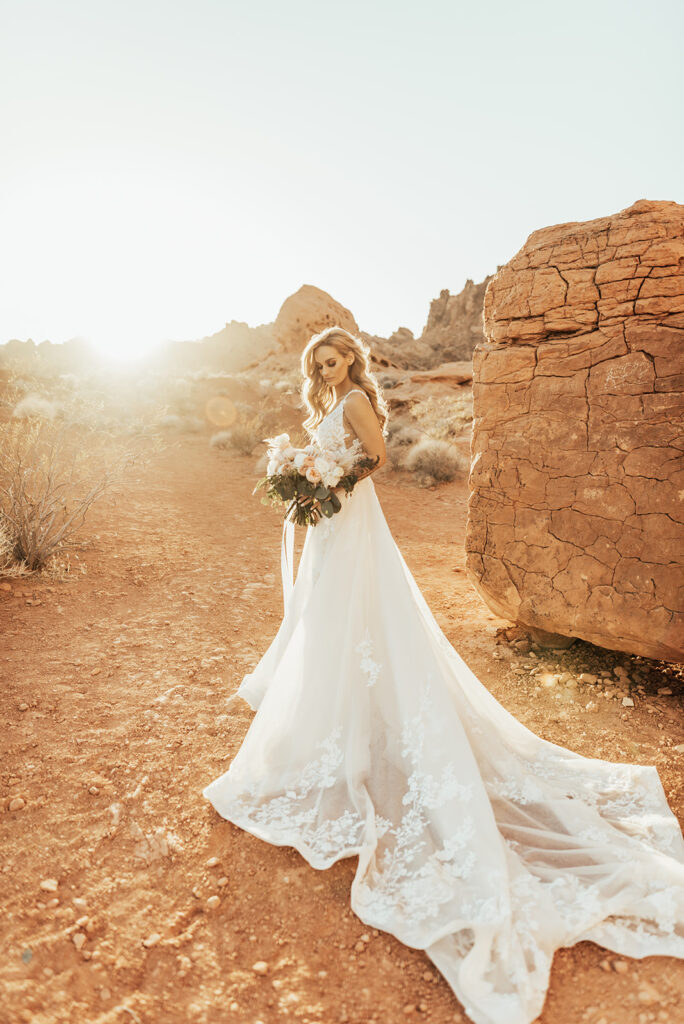 The Ultimate Guide to Different Types of Wedding Dresses: From Classic to Contemporary. Bride in a boho style long lace v=neck wedding dress. With a wide angle dramatic shot, the bride stands just in front of the sun at sunset in the Las Vegas Desert. 