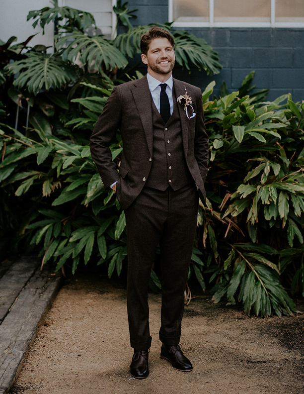 Groom attire of a dark brown suit and vest. 