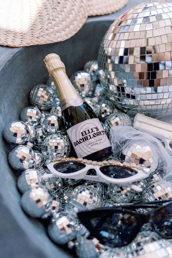 5 Trendiest Bach Party Themes Decor with disco balls, sun glasses, and tiny personalized champagne bottle with brides name on it. Matching the Glits and Glam Theme. 