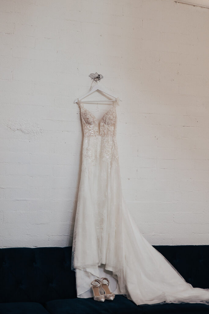 The Ultimate Guide to Different Types of Wedding Dresses: From Classic to Contemporary Classic lace wedding gown handing on the hanger against a white wall. 