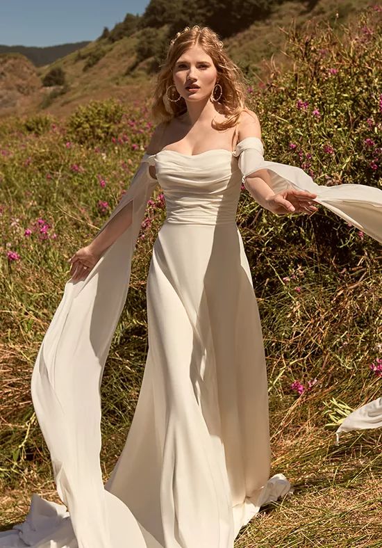 Unveiling the Magic: The Art of Styling a Themed Wedding fitted wedding dress with sweetheart neckline. Standing in a field with long dramatic floor length sleeves. 