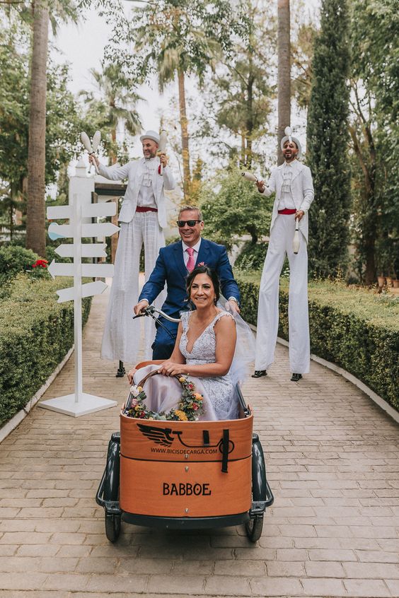 Professional performers juggle behind the couple as they ride in a fun little bike and cart for their grand entrance. 
