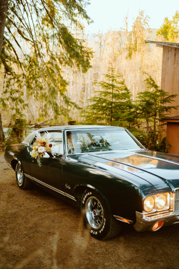 Bride and groom sitting in an old school blue green muscle car. Arriving for their wedding. 