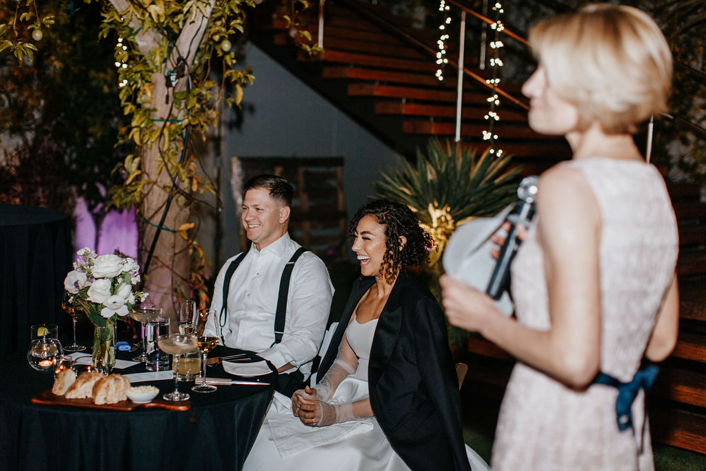 Couple at sweetheart table during wedding reception toast