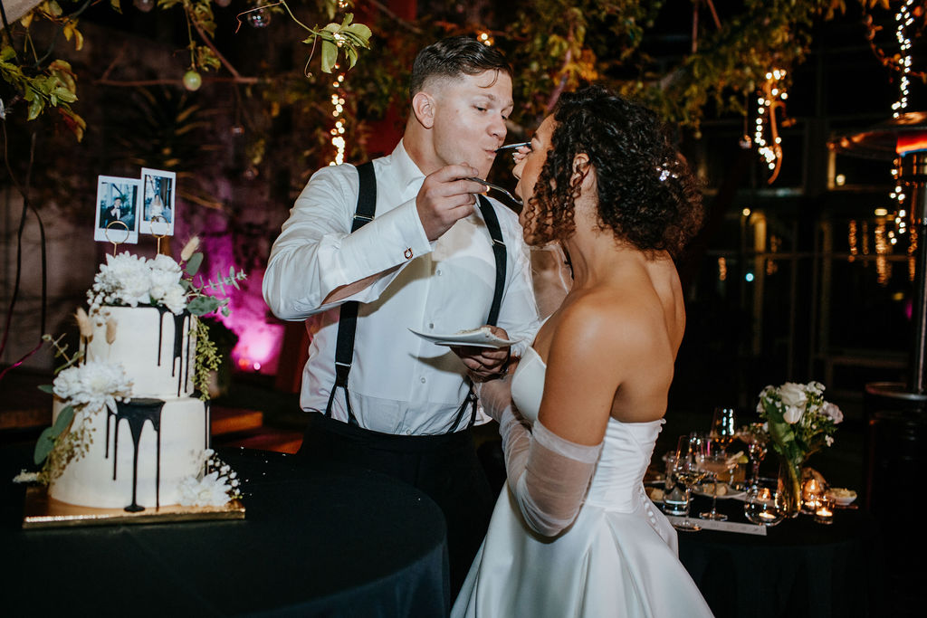Unleash the Magic: Why Your First Look Should Steal the Show. Newlyweds feeding each other cake 