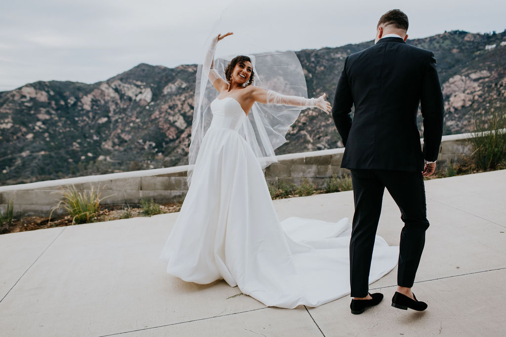 Unleash the Magic: Why Your First Look Should Steal the Show. Bride with her hands up showing groom dress during first look 