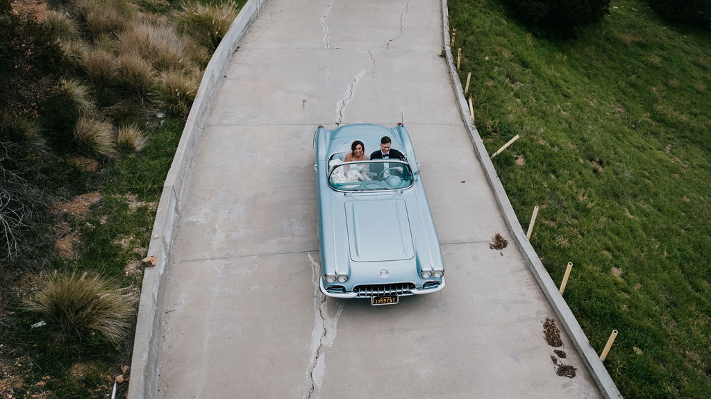 Unleash the Magic: Why Your First Look Should Steal the Show. Bride and groom driving in classic  car 