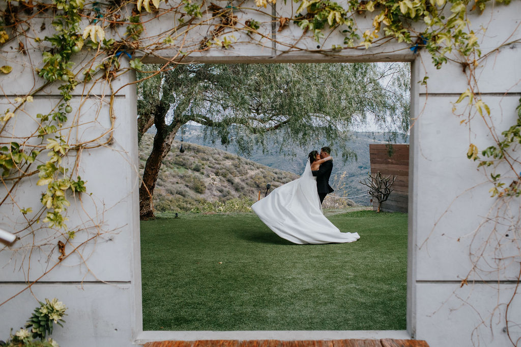 Unleash the Magic: Why Your First Look Should Steal the Show. Bride and groom kissing through concrete square cut out. 