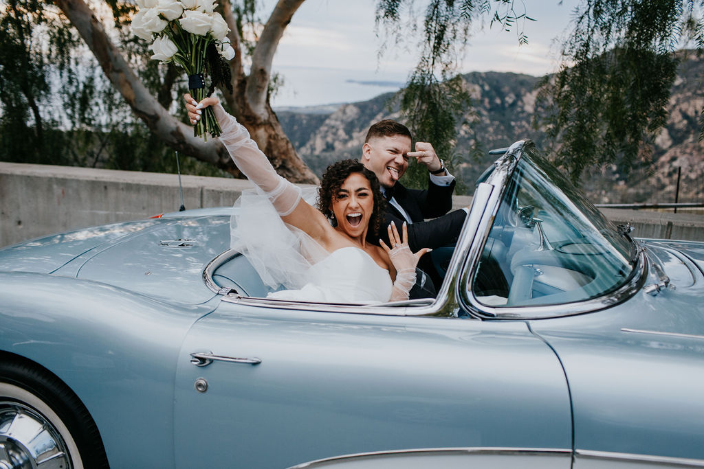 Unleash the Magic: Why Your First Look Should Steal the Show. Bride and groom celebrating in classic  blue car 
