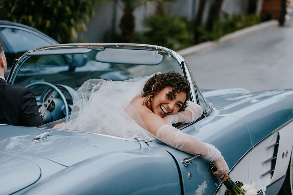 Bride leaning out classic  convertible car 
