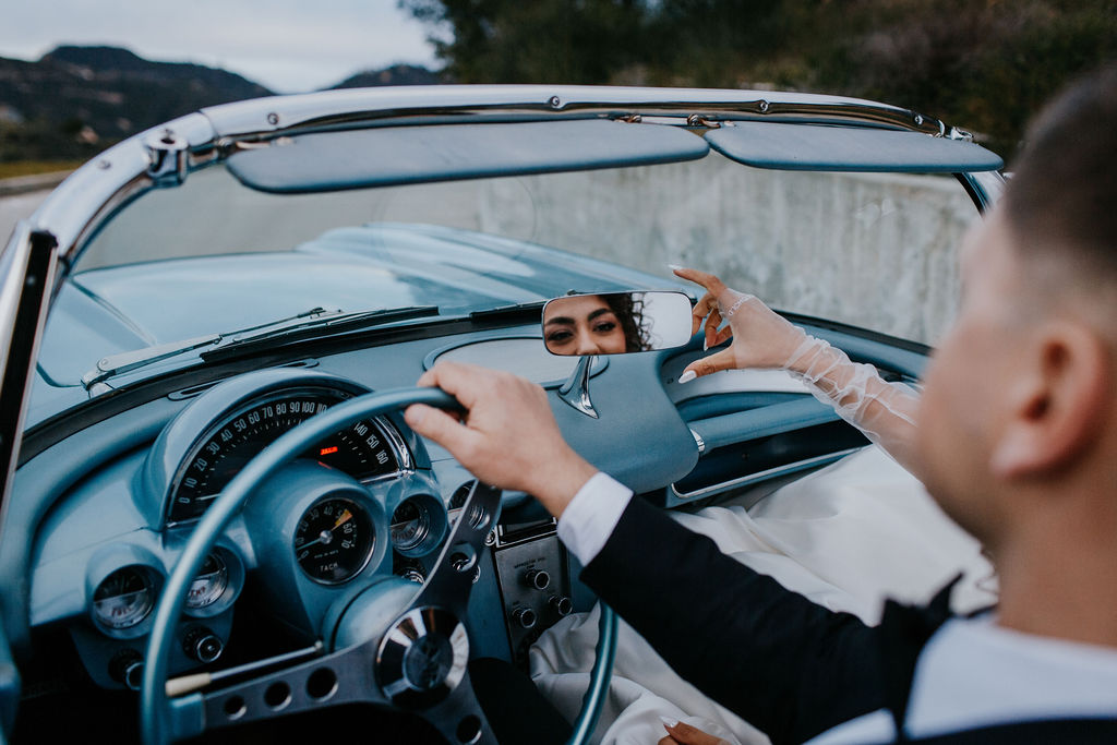 Bride and groom driving in classic  blue car 