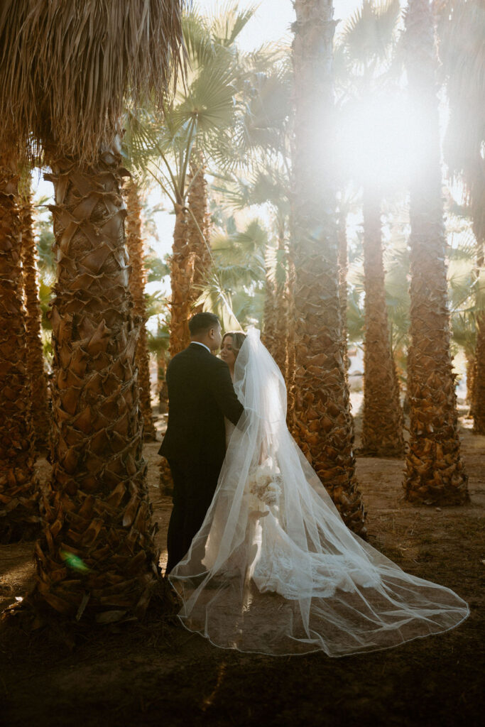 Bride and Groom surrounded by palm trees while sun sets 