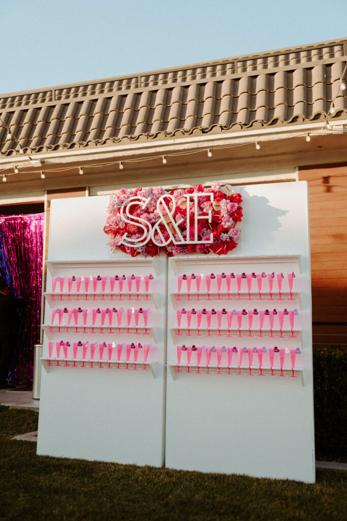 Champagne wall with pink cups and sign 