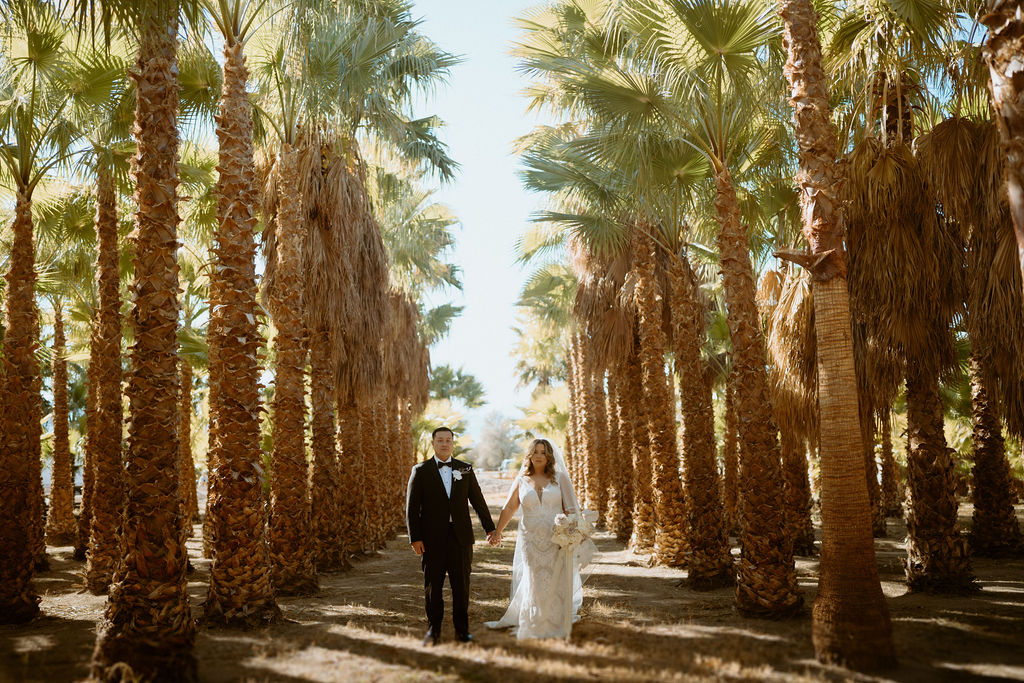 Newlyweds walking through palm trees 
