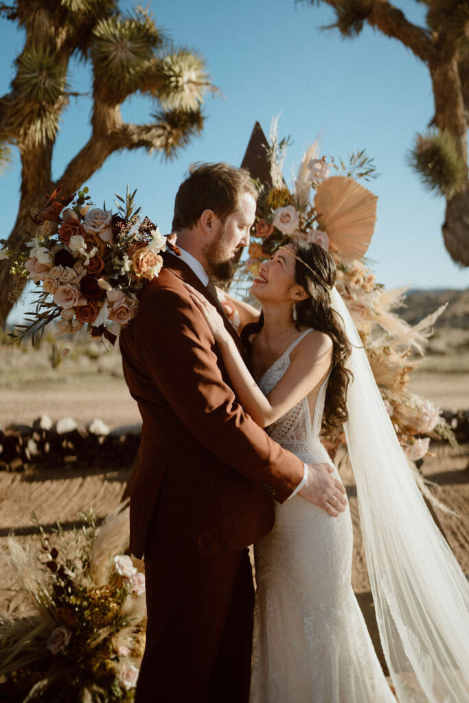 Intimate Elopement at Rimrock Ranch in Joshua Tree California. Newlyweds smiling with Triangle Arch 