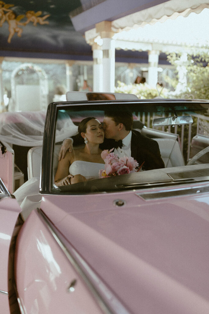 Couple in pink Cadillac at A little white wedding chapel 