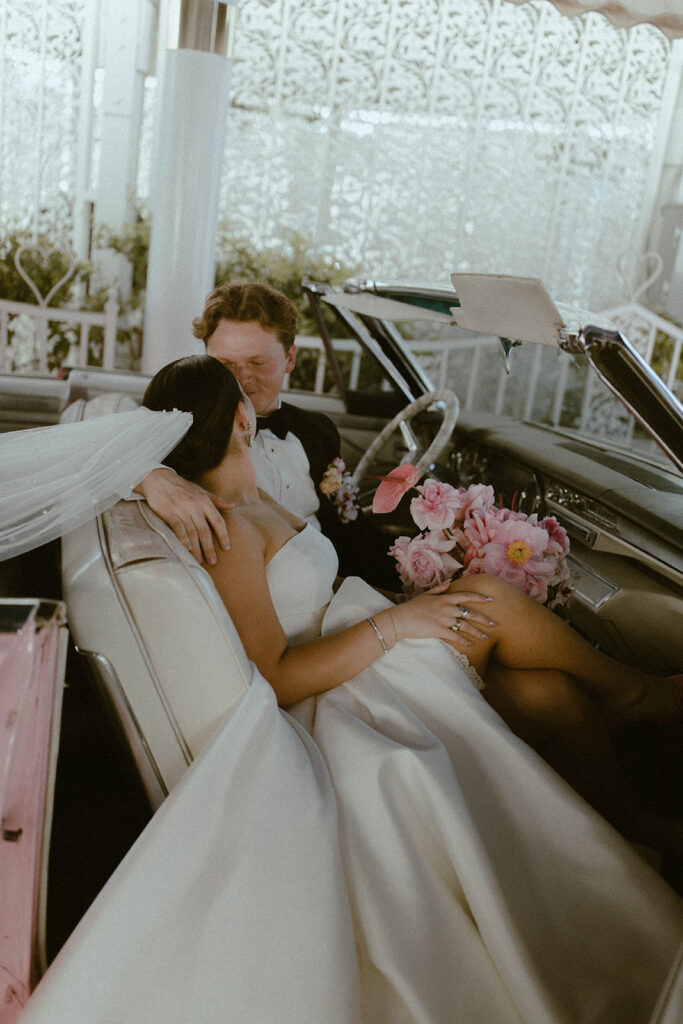 Couple in pink Cadillac at A little white wedding chapel 