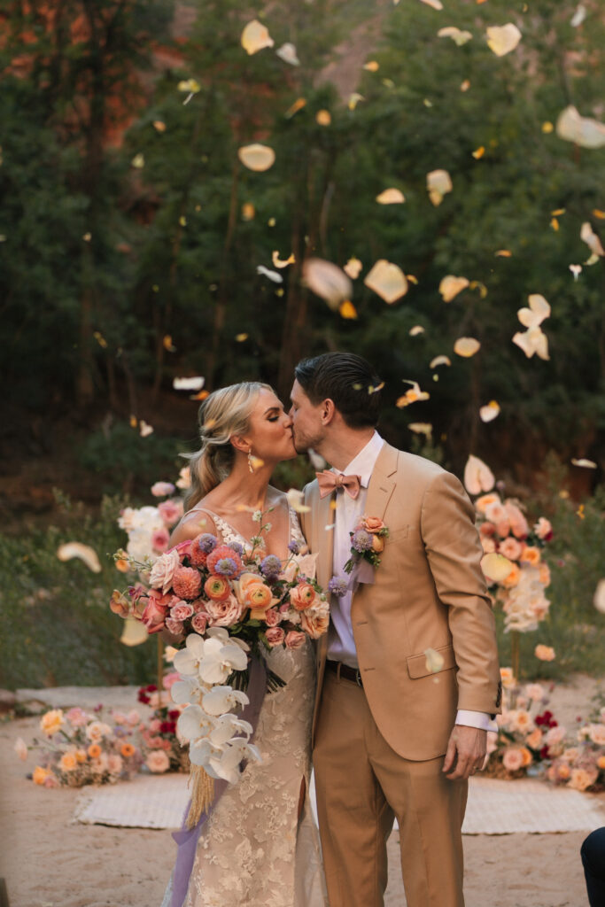 Beyond Vows: The Epic Zion National Park Wedding flowers in the air with couple