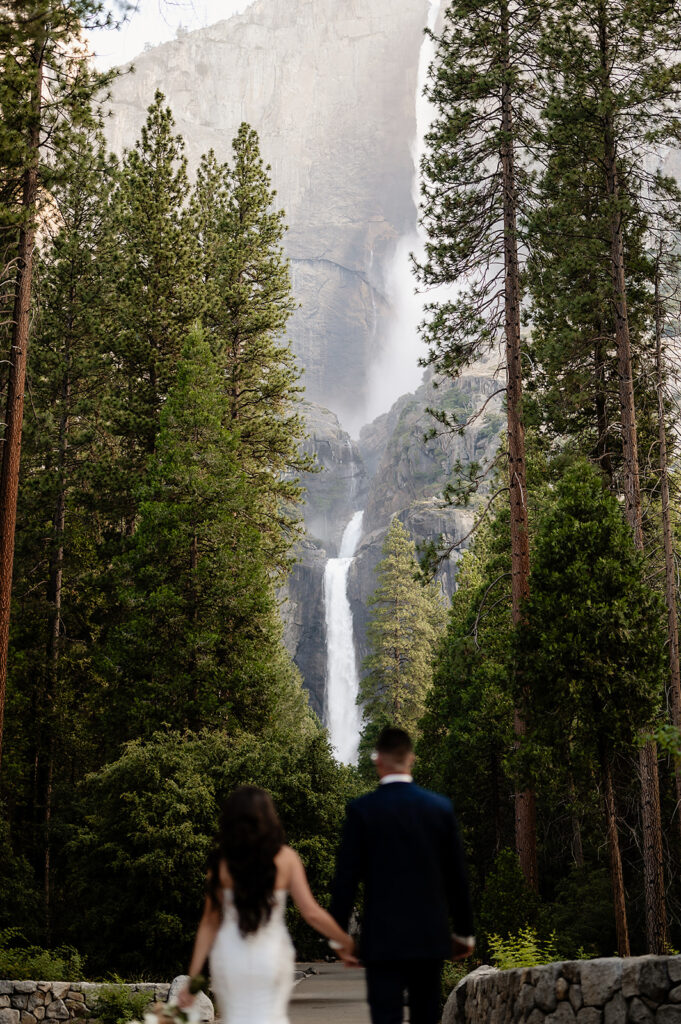 Bride and groom walking toward waterfall 