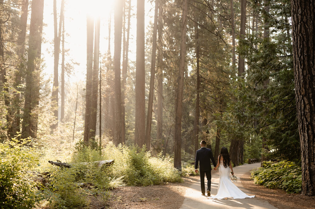 Yosemite Micro-Wedding: Why Intimate Celebrations are a Vibe. Bride and Groom walking through forest during sunrise 