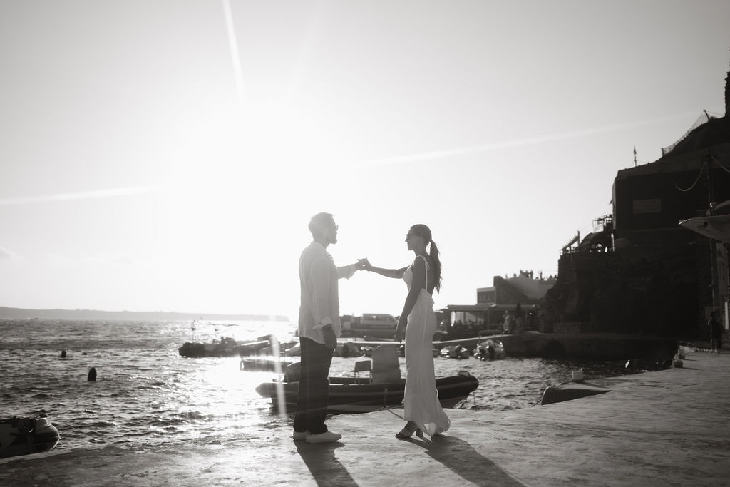 A couple holding hands by the sea,  at their post wedding session in Santorini Greece