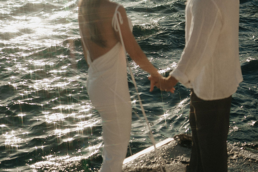 A couple holding hands by the sea,  at their post wedding session in Santorini Greece