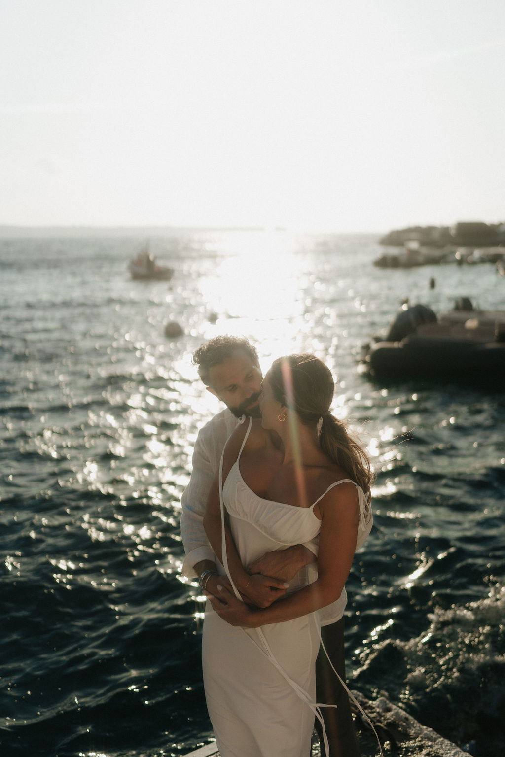 A couple holding each other by the sea, at their post wedding session in Santorini Greece
