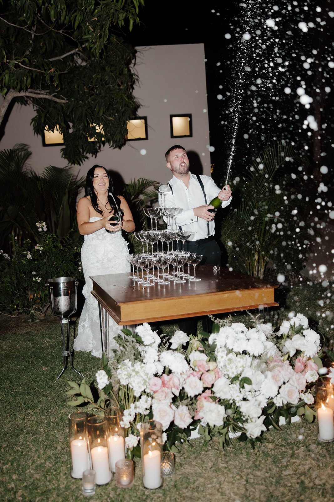 Bride and groom perform a champagne tower pour at their wedding reception.