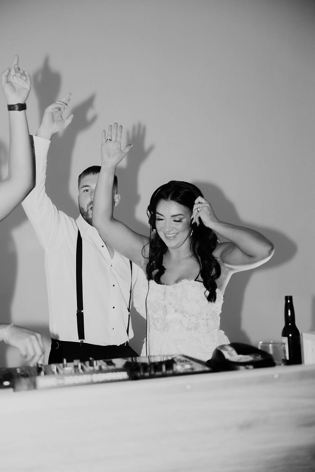A couple enthusiastically dancing with raised arms at their wedding, captured in black and white.