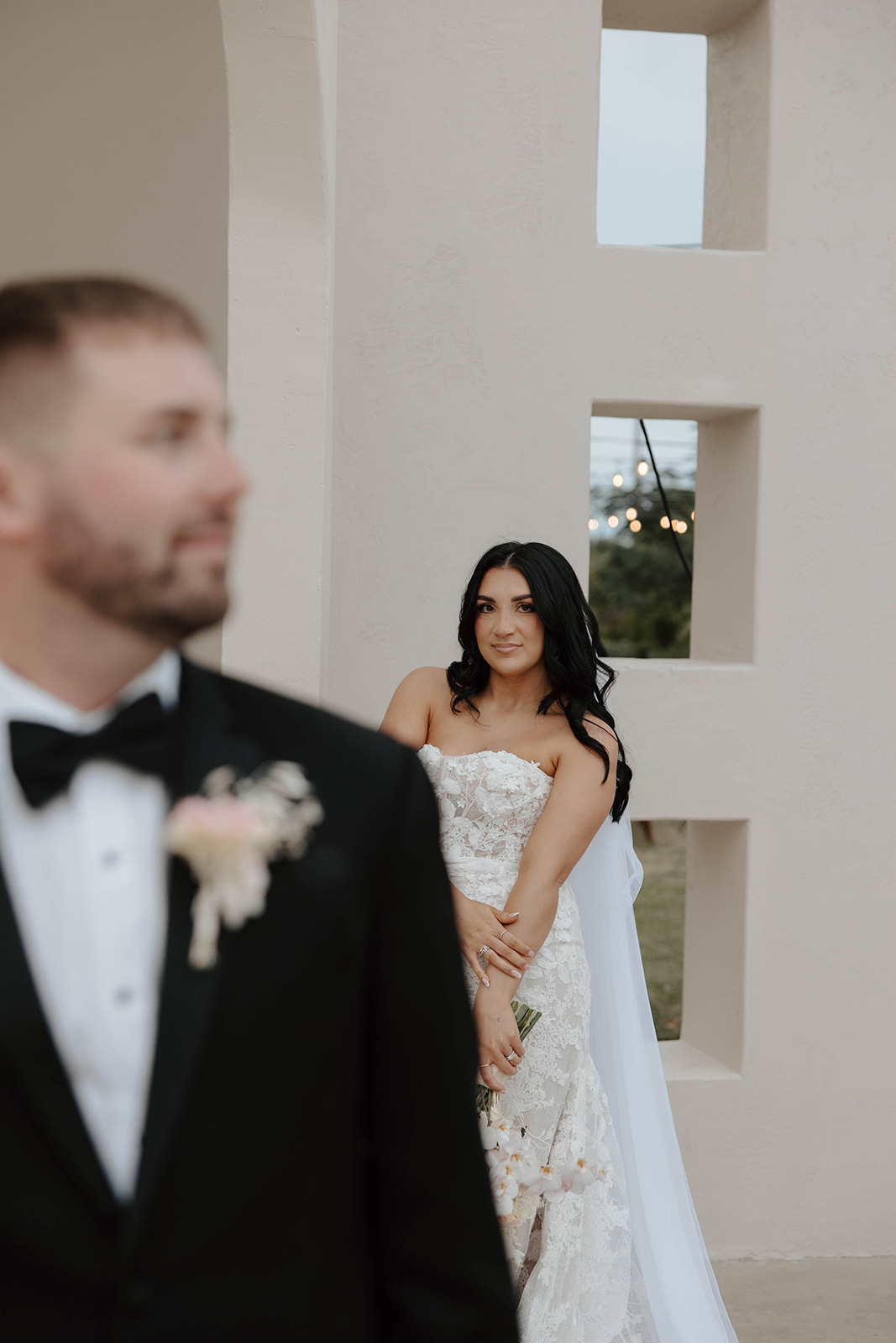 A newlywed couple walking hand in hand with a joyful expression as wedding guests look on.