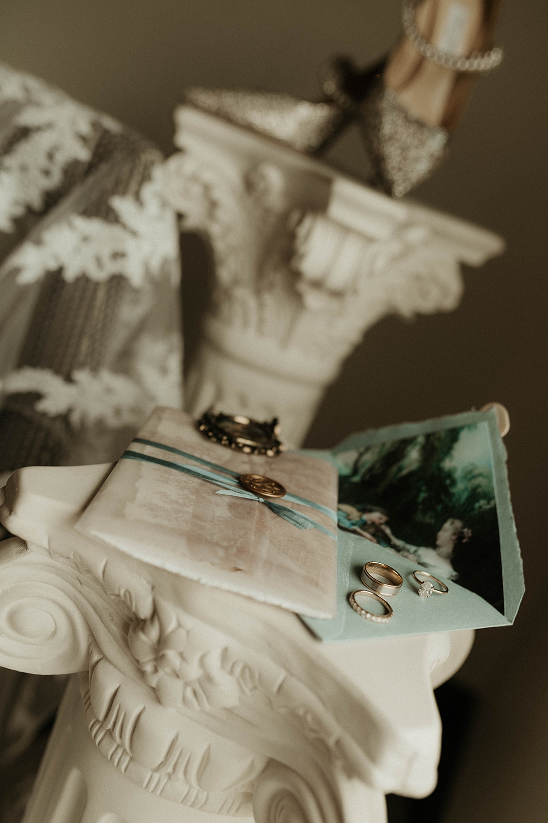 An antique-style photo featuring a stack of vintage wedding invitations, a romantic painting, a ribbon, and old jewelry on a creamy fabric background for a bridgerton wedding