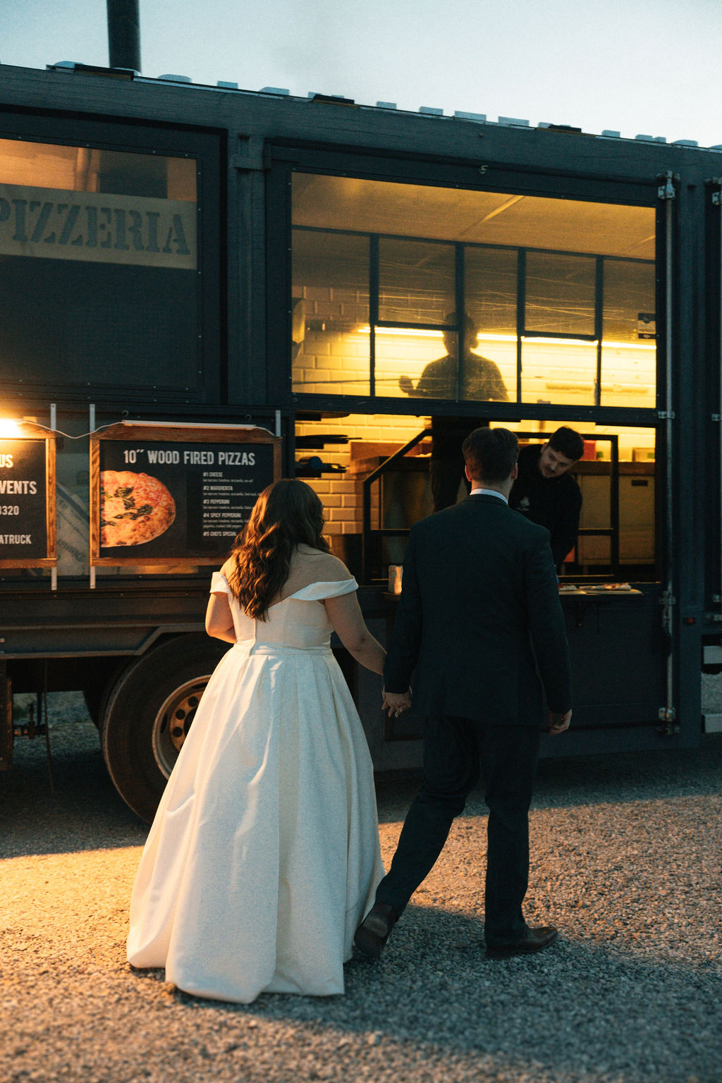 couple at their wedding reception ordering pizza from a truck 